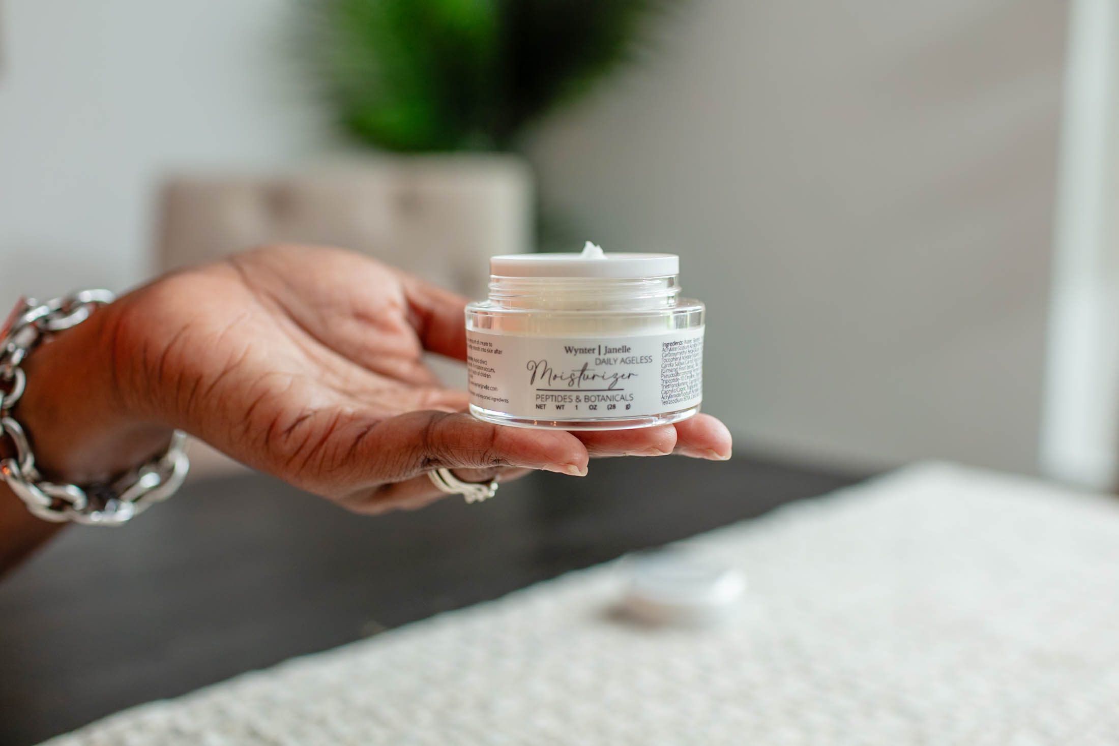 Hand holding a jar of face cream.